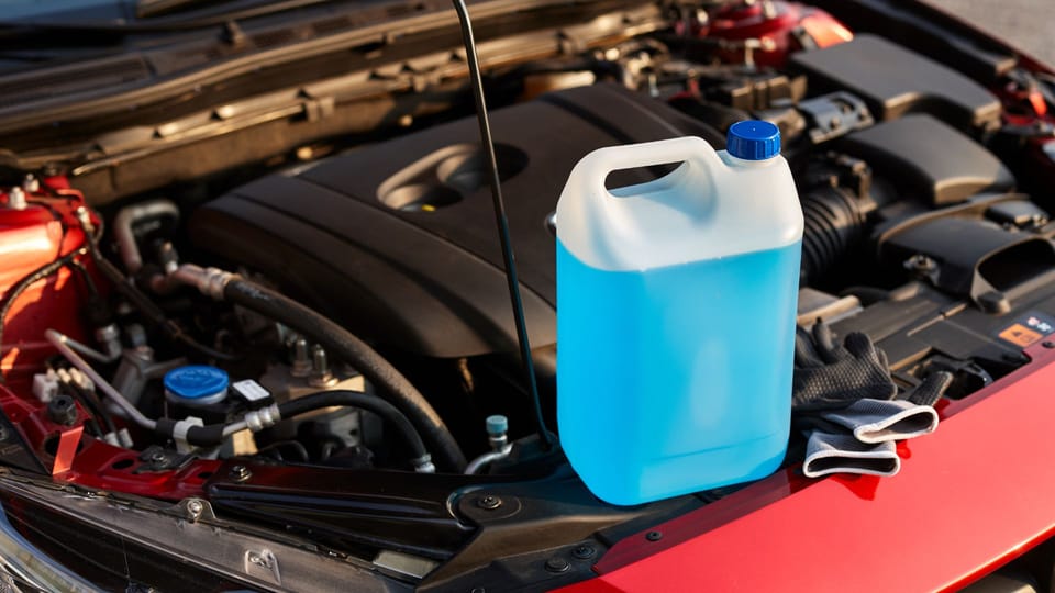 a blue canister sitting on top of a red car.|a person is holding a metal object in their hand.
