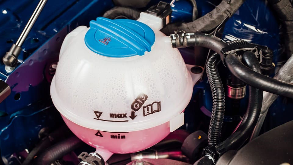 a close up of the engine of a car.|a woman standing next to a car with its hood open.|a woman talking on a cell phone next to a car.|a plastic container with a yellow cap on the hood of a car.|a man is filling up a car engine.