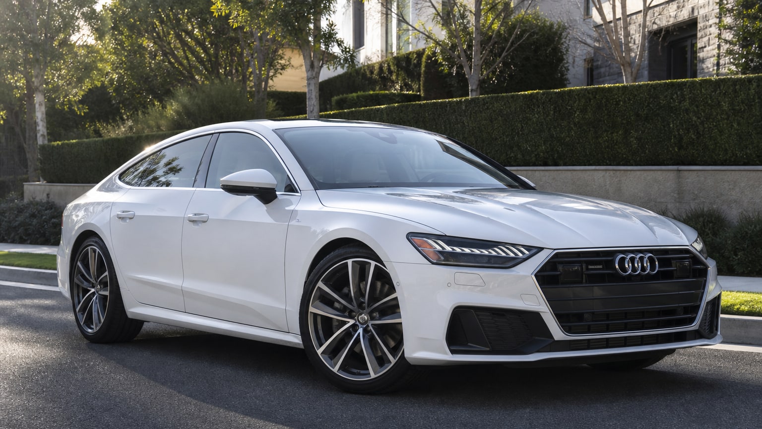 A modern Glacier White Audi A7 on a quiet upscale street.