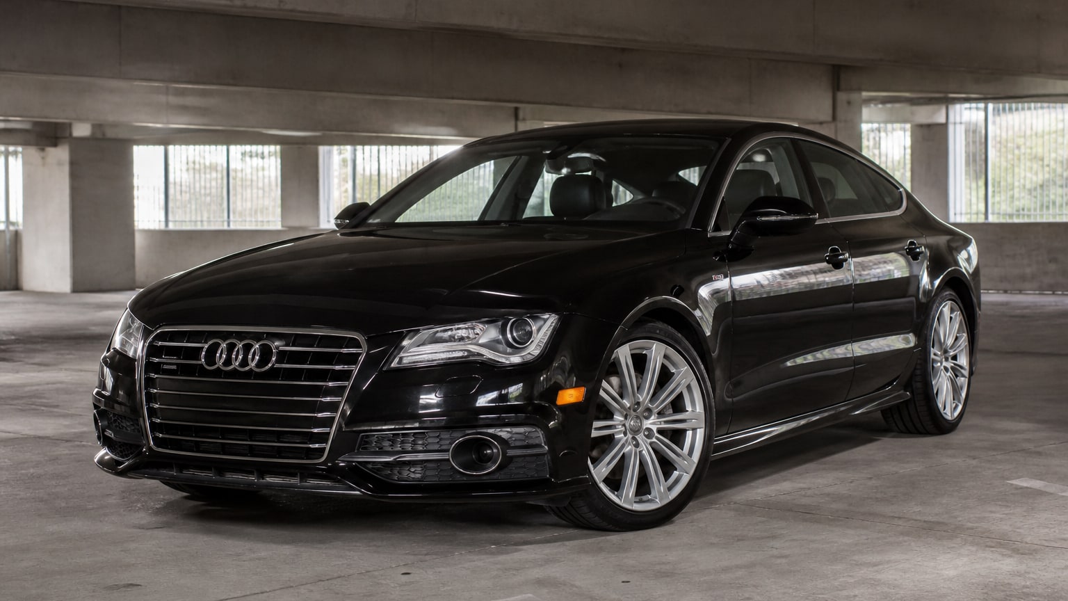 A black 2012–2013 Audi A7 parked in a concrete parking garage.