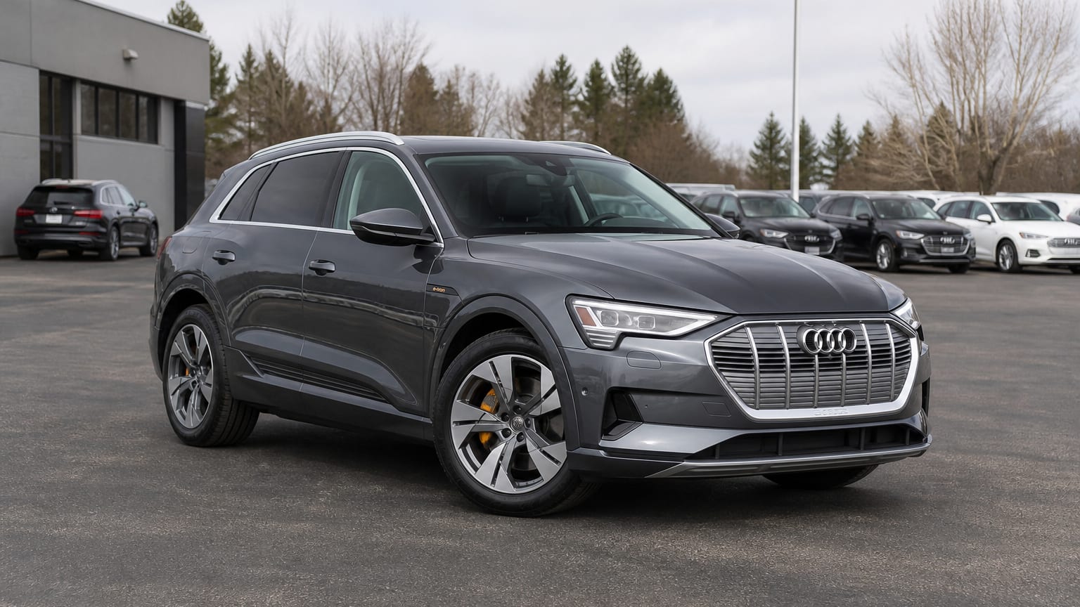 A dark gray 2019 Audi e-tron parked in a dealership lot.