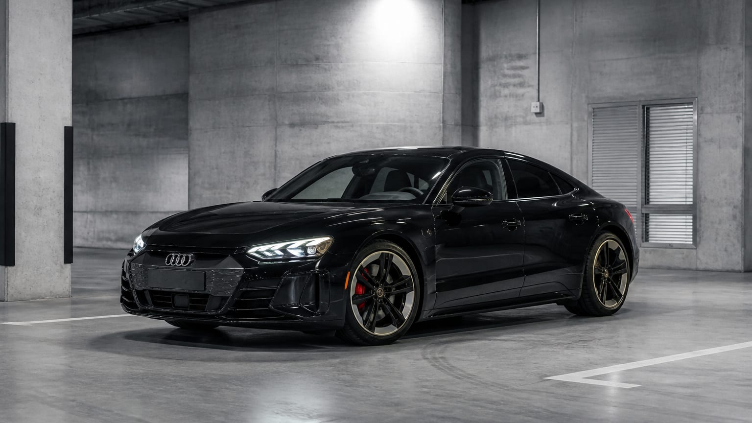 A dark 2022–2023 Audi e-tron GT parked in a concrete garage.