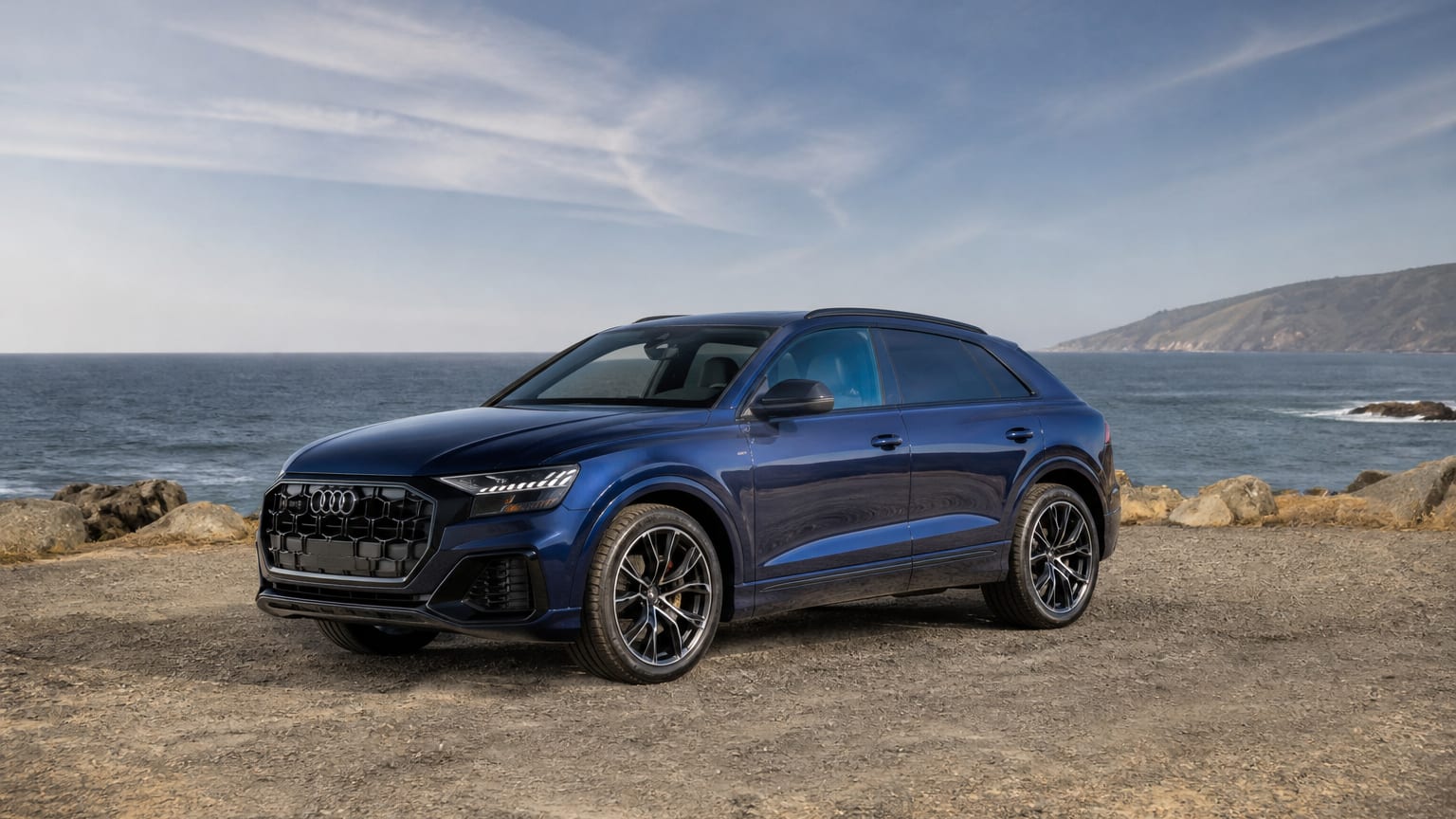 A dark blue Audi Q8 SUV parked at a waterfront overlook.