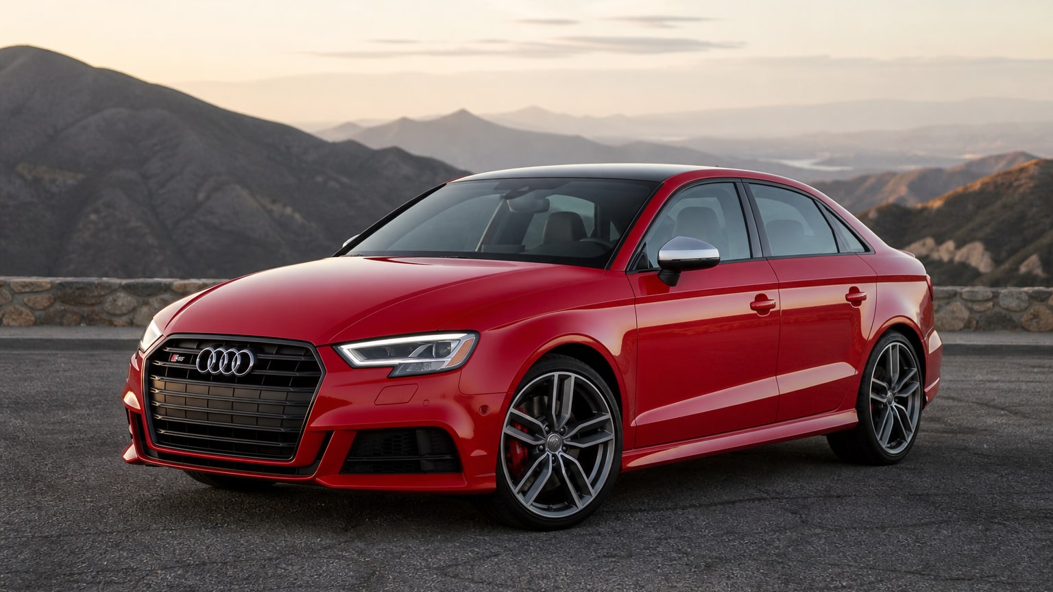 A red Audi S3 sedan parked on an empty canyon road overlook.