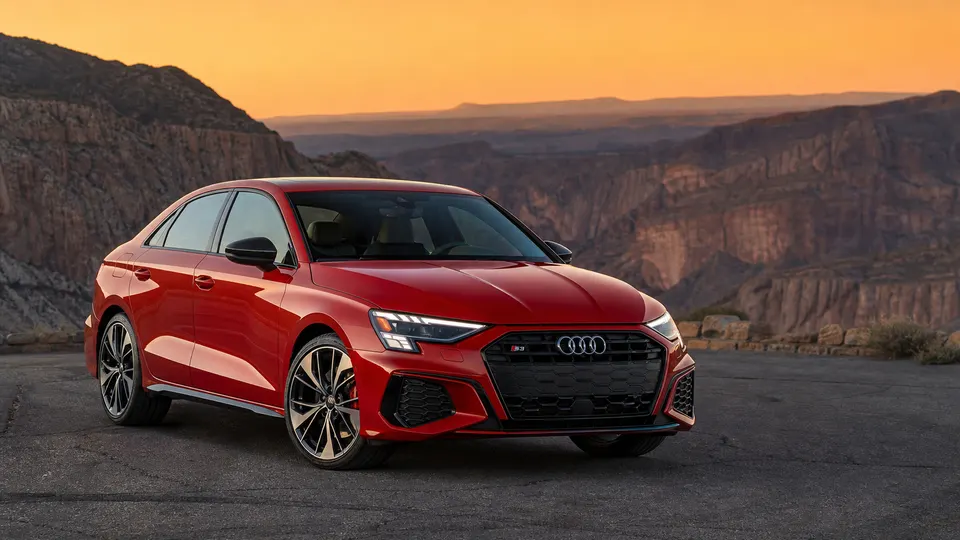 A red Audi S3 sedan, three-quarter front view, parked on an empty canyon road.