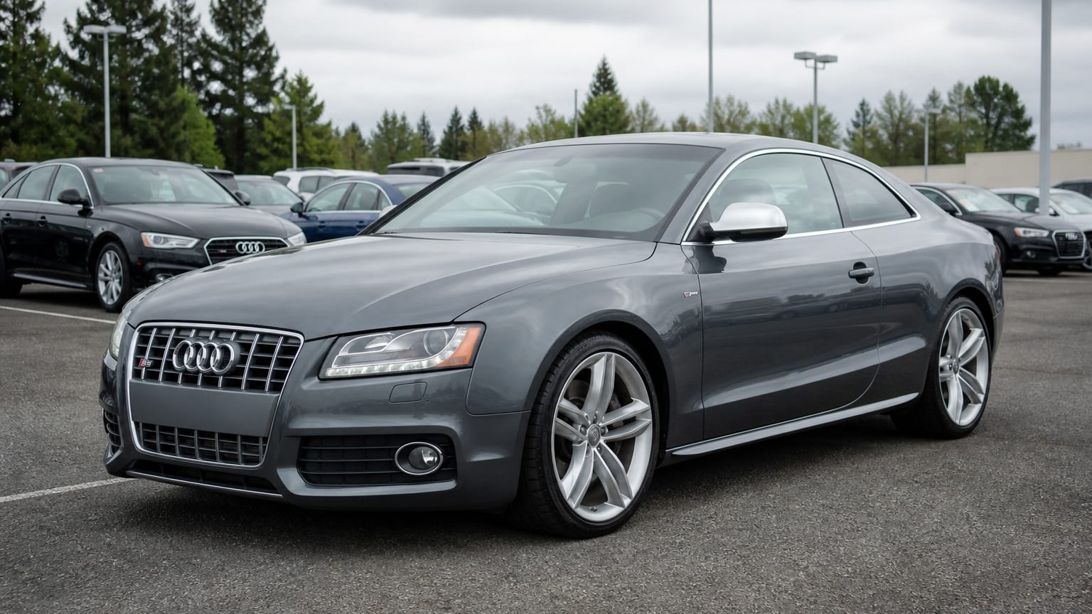 A dark gray 2008–2015 Audi S5 coupe parked in a dealership lot.