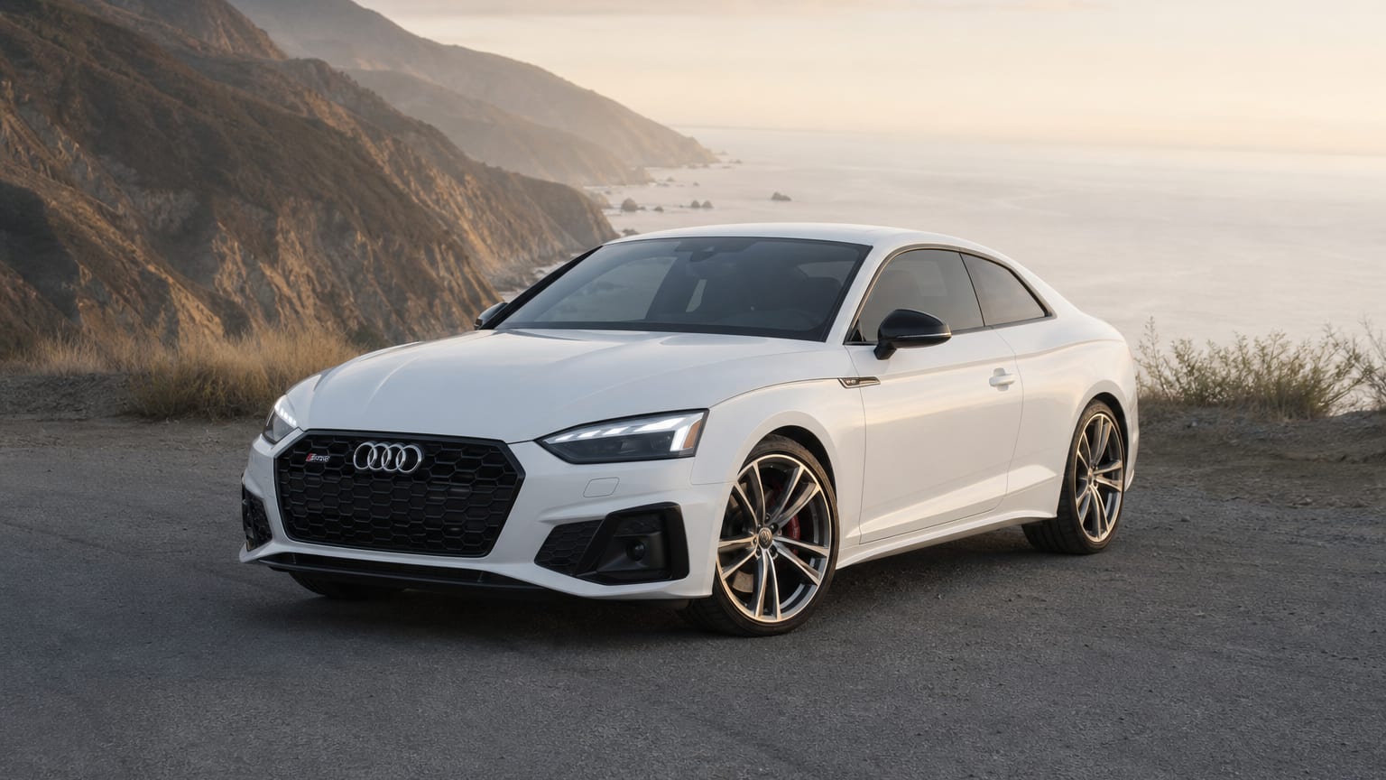 A Glacier White Audi S5 coupe parked on a coastal canyon overlook.