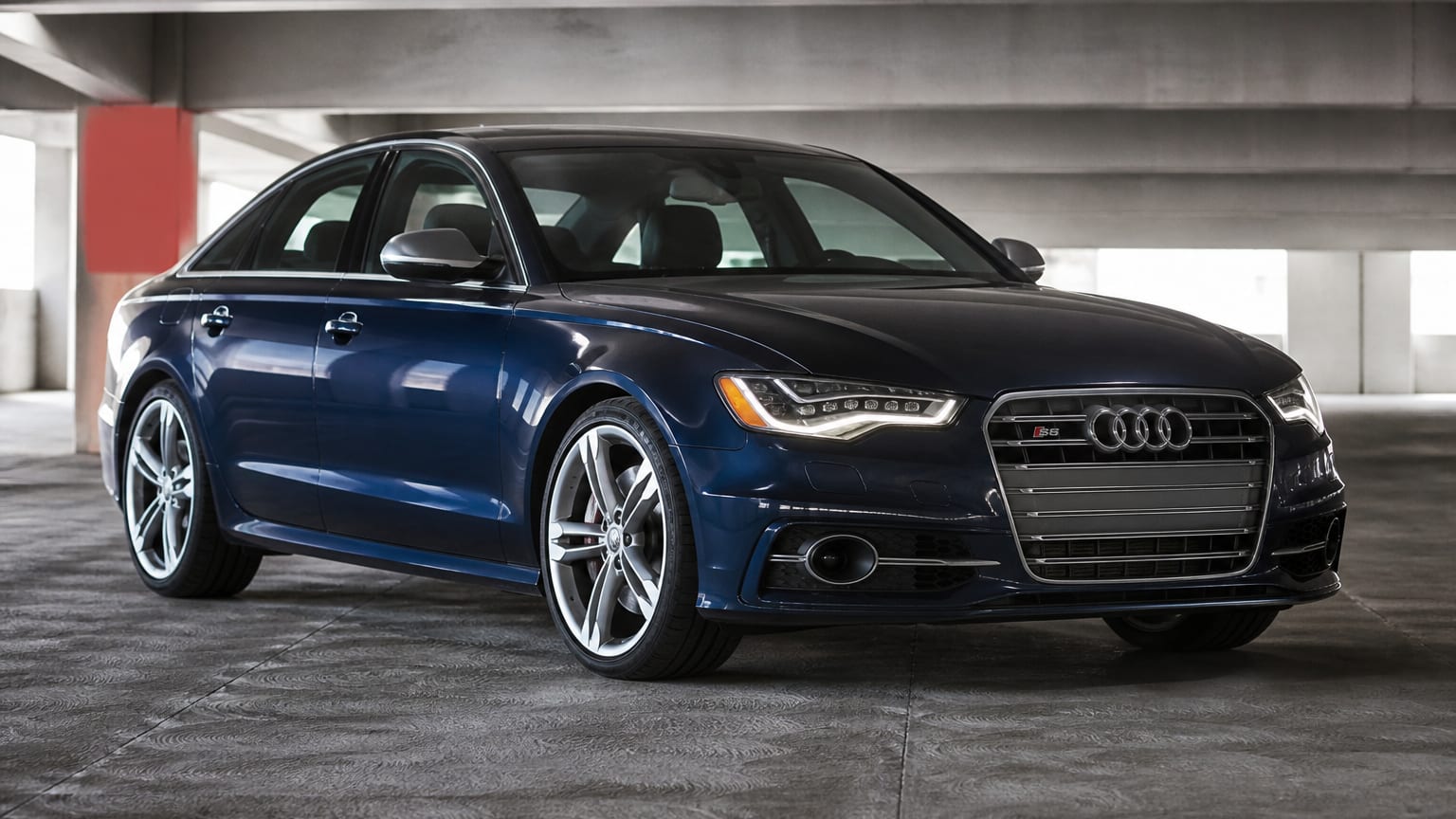 A dark blue 2013–2014 Audi S6 parked in a concrete parking garage.
