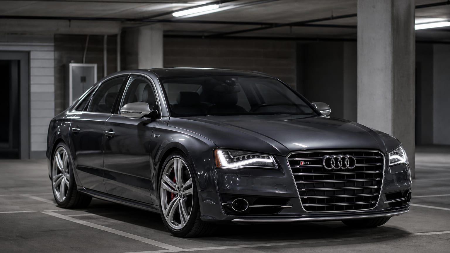 A dark gray 2013–2017 Audi S8 parked in a subterranean garage.