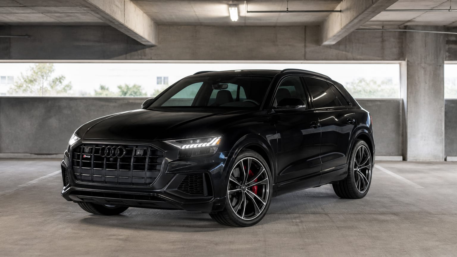 A black 2021 Audi SQ8 parked in a concrete parking garage.