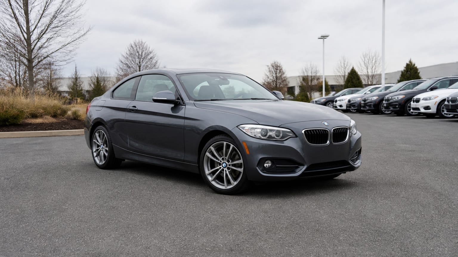 A gray 2014–2017 BMW 2 Series coupe parked in a dealership lot.