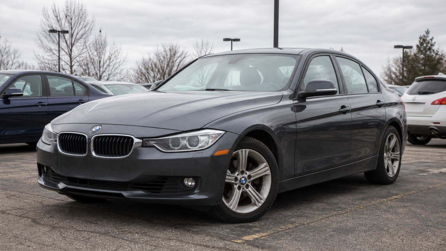A dark gray early-2010s BMW 3 Series sedan in a dealership lot.