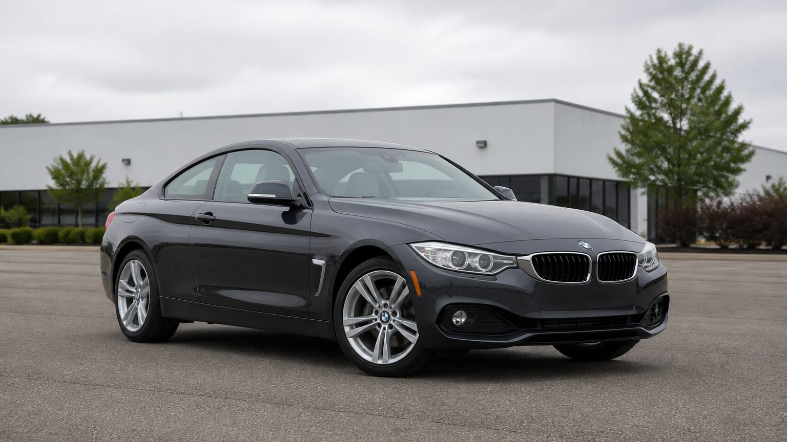 A dark gray 2014–2015 BMW 4 Series coupe parked in a dealership lot.