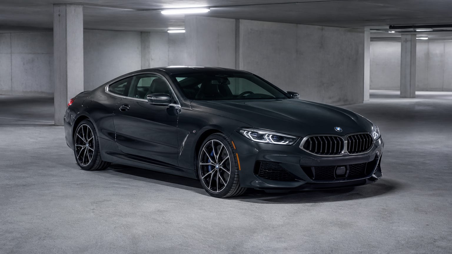 A dark 2019–2021 BMW 8 Series coupe parked in a concrete garage.