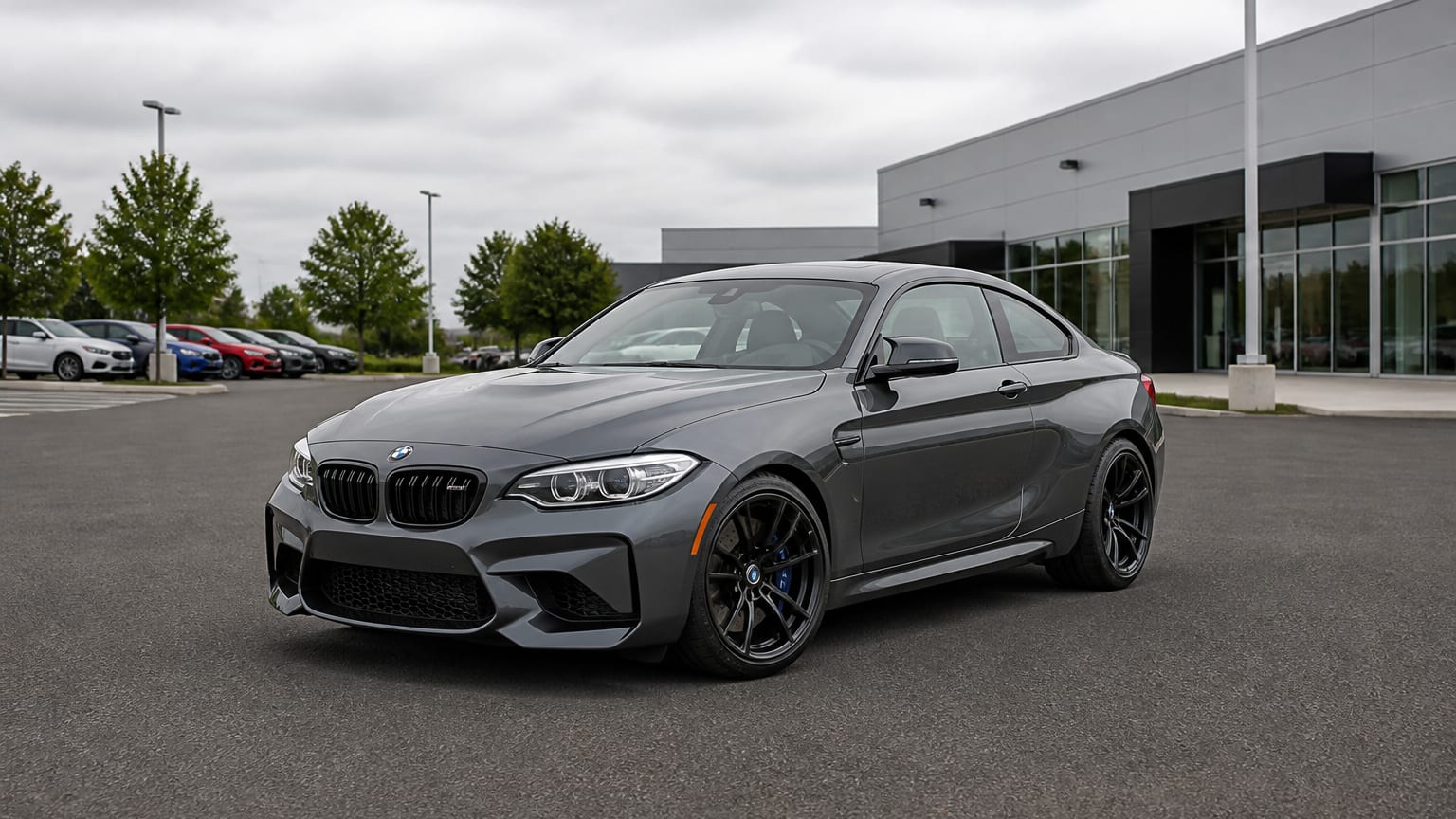 A gray 2016 or 2023 BMW M2 parked in a performance dealership lot.