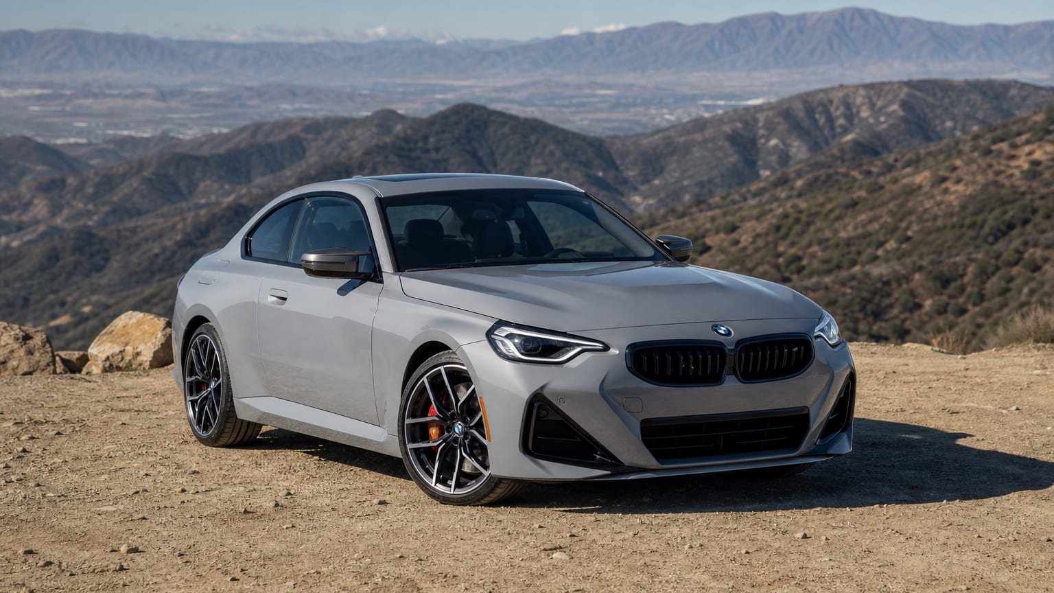A late-model 2022–2024 BMW M240i on a mountain overlook.
