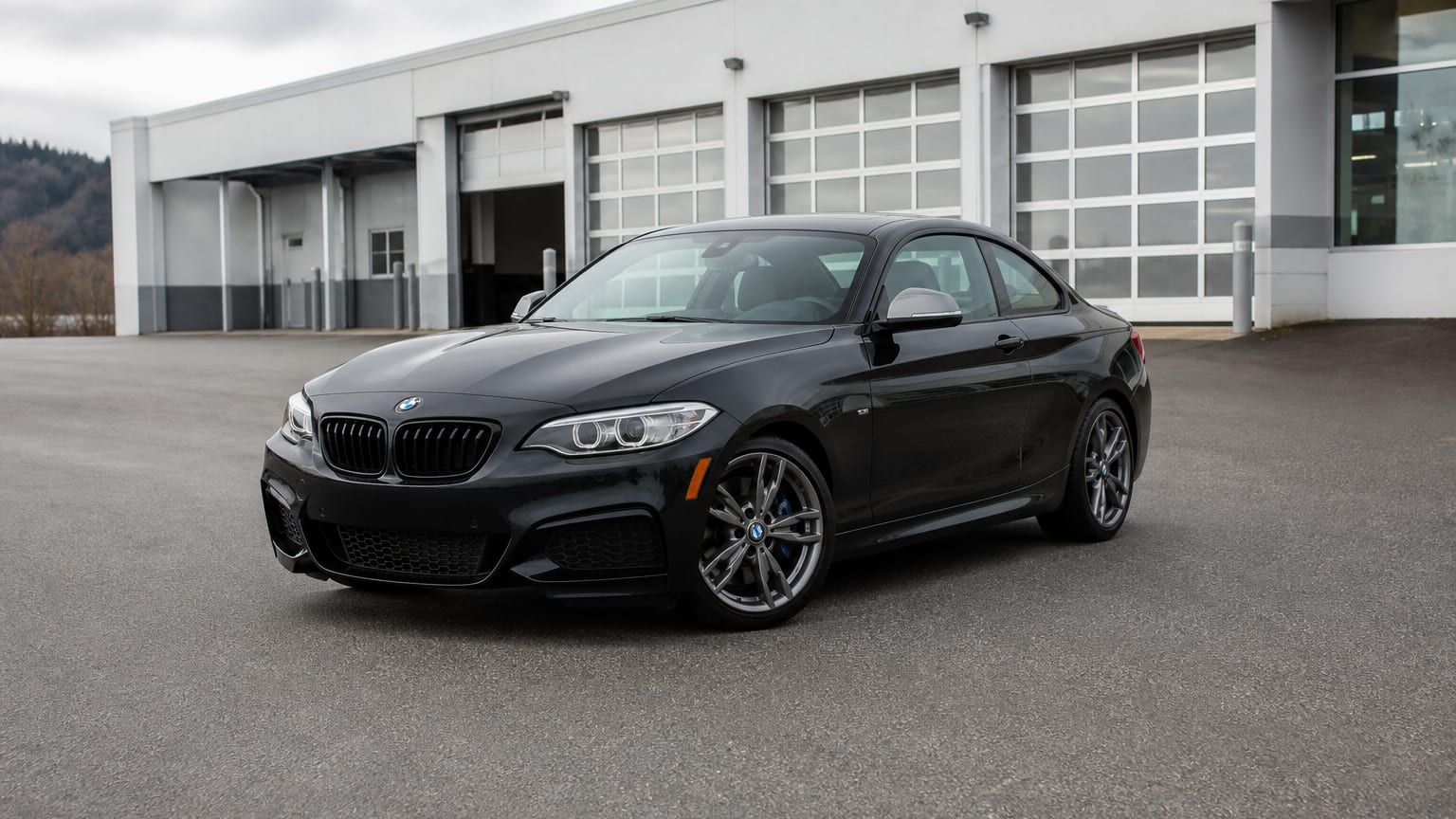 A dark 2019–2020 BMW M240i parked in a dealership service lane.