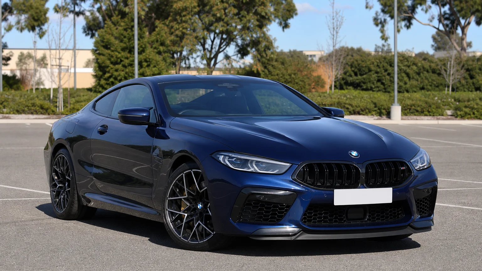 A BMW M8, three-quarter front view, parked outdoors.