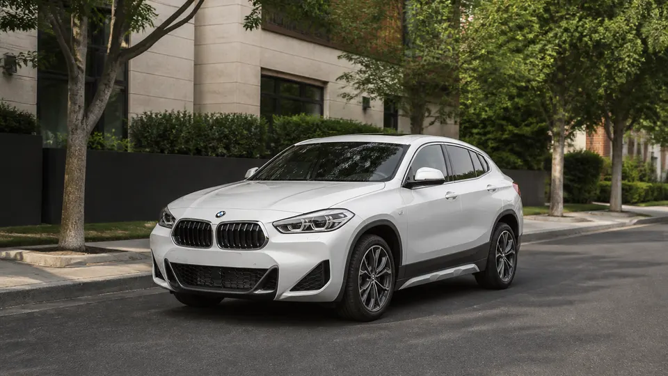 An Alpine White BMW X2 crossover, three-quarter front view, parked on a city street.