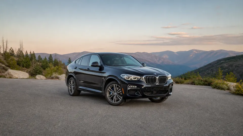 A Black Sapphire BMW X4 coupe-SUV, three-quarter front view, parked on a mountain overlook.