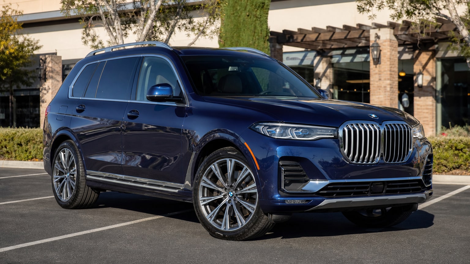 A dark blue 2019 BMW X7 parked in a shopping center lot.