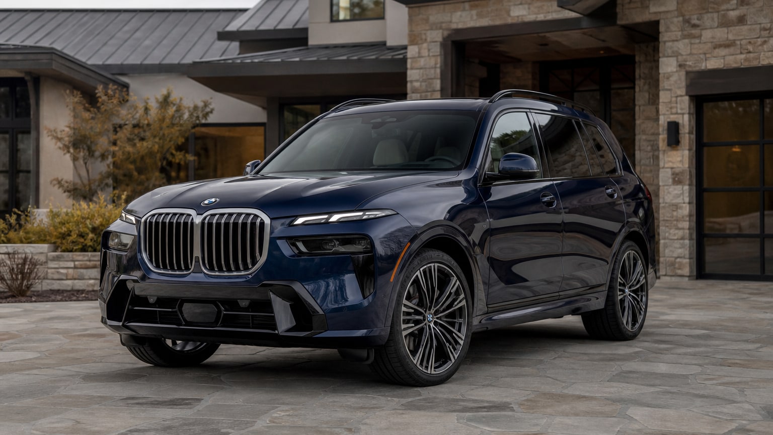 A black BMW X7 three-row luxury SUV parked on a tree-lined street.