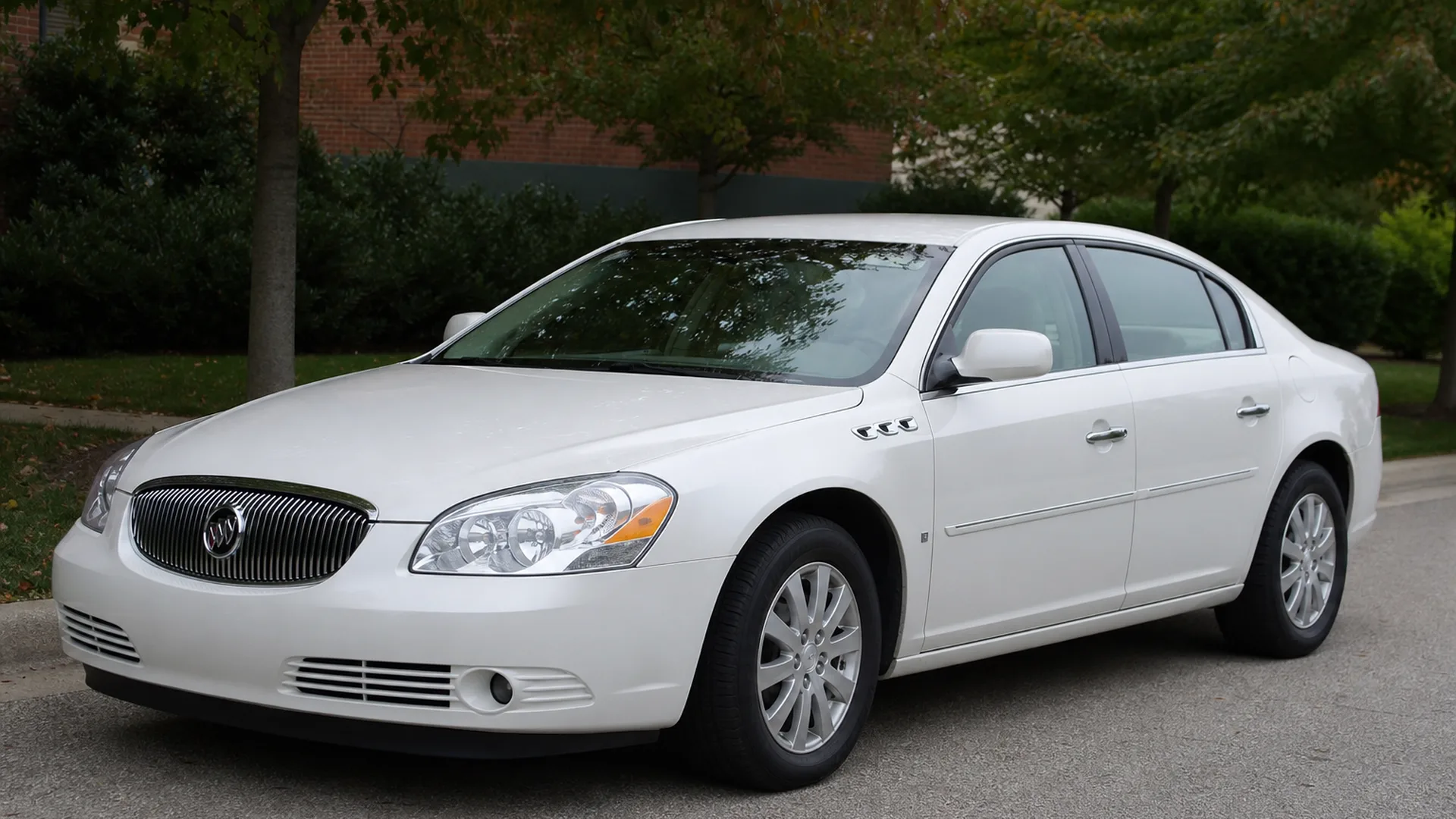 A white Buick Lucerne sedan parked on a street.