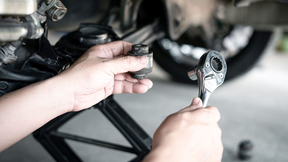 a close up of a person holding a wrench.|a man working on a vehicle with a wrench.