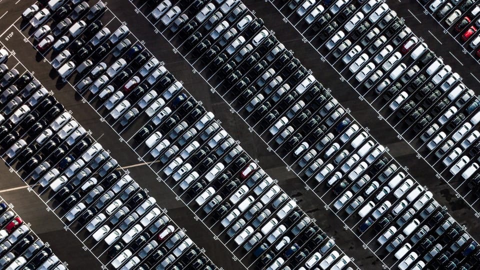 a parking lot filled with lots of parked cars.|an assembly line with a car being worked on.|an assembly line with cars on the assembly line.
