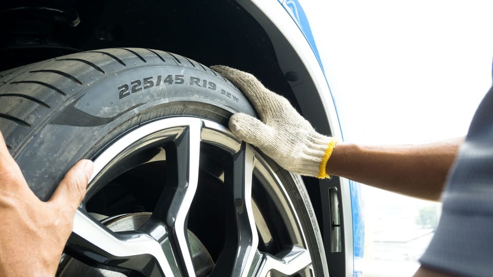 a person checking tire markings on a car wheel.