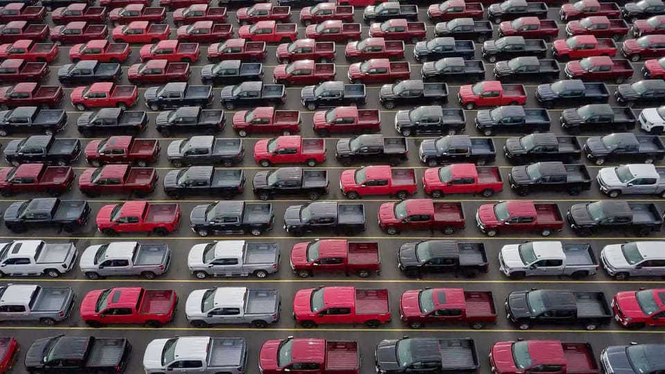 a large parking lot filled with lots of cars.|a green sports car parked in front of a building.|a red car parked on the side of a road.