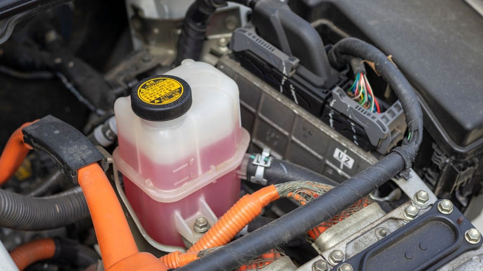 the engine compartment of a car with a fuel can.|a man is working on a car's engine.