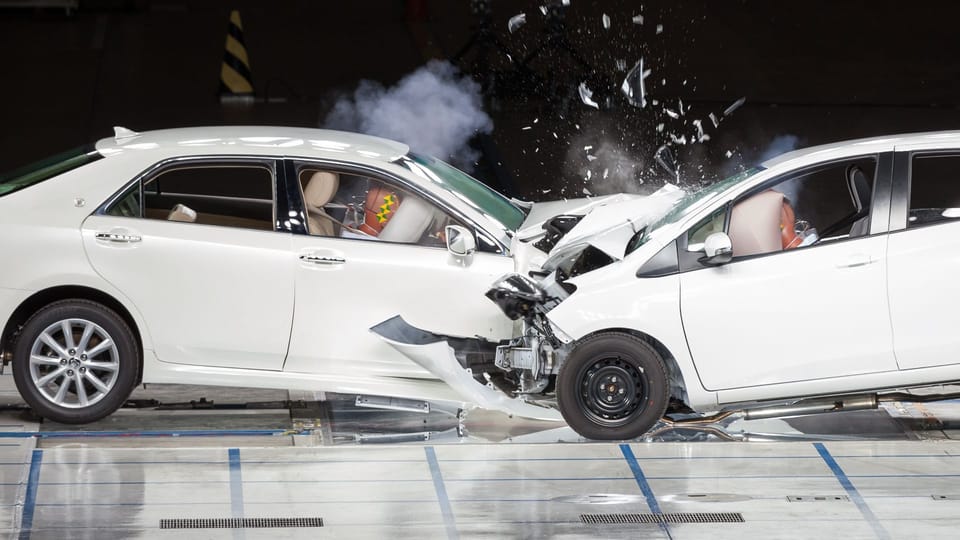 a couple of cars that are in a garage.|a close up of a white car with black paint on it.