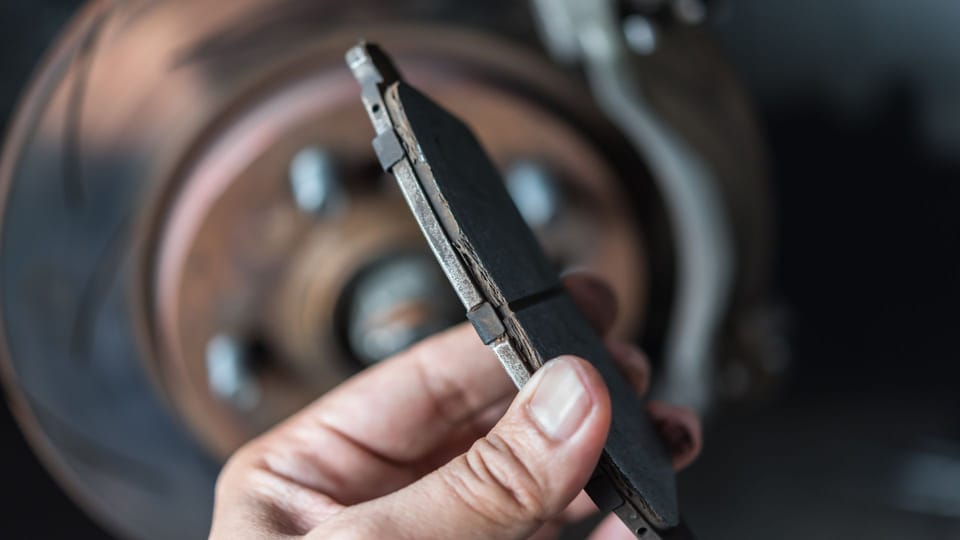 a man working on a brake assembly on a car.