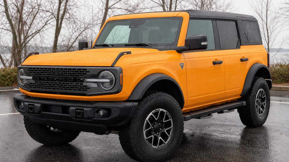 An orange early sixth-generation Ford Bronco four-door parked outdoors.