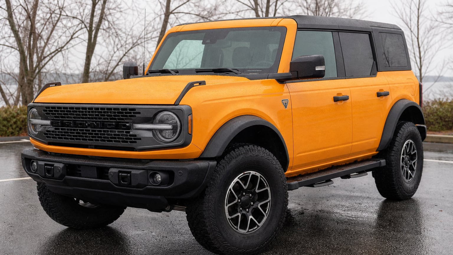 An orange early sixth-generation Ford Bronco four-door parked outdoors.