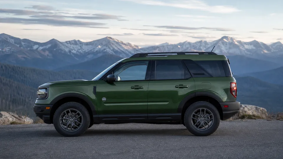 A green Ford Bronco Sport compact SUV in side profile at a mountain overlook.