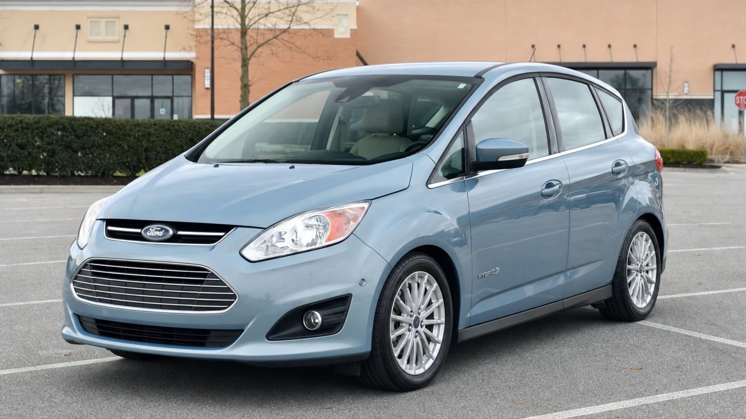 A blue 2013 Ford C-Max Hybrid hatchback parked in a shopping center lot.