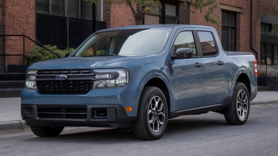 A blue 2024 Ford Maverick compact pickup truck parked on a city street.