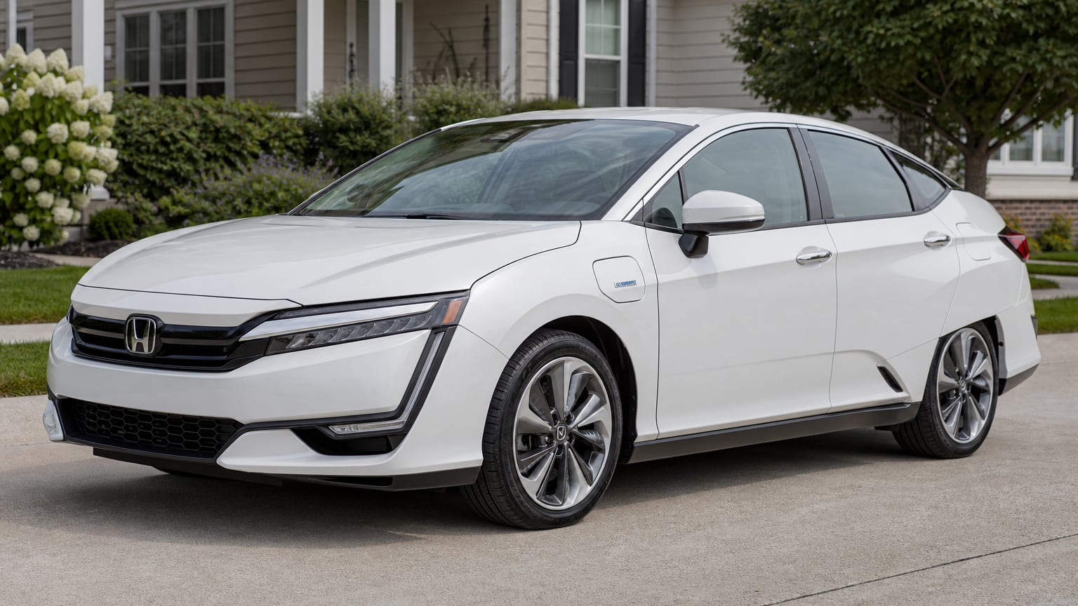 A white Honda Clarity Plug-In Hybrid sedan parked on a suburban driveway.