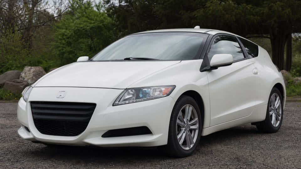 A white early Honda CR-Z hybrid coupe parked outdoors.
