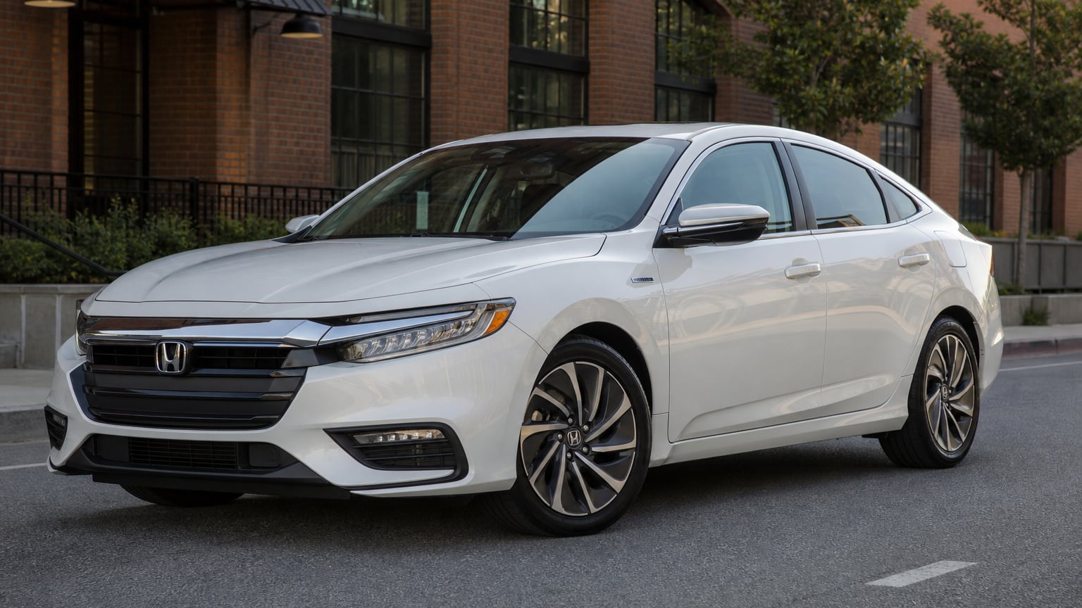 A white third-generation Honda Insight hybrid sedan parked on a city street.