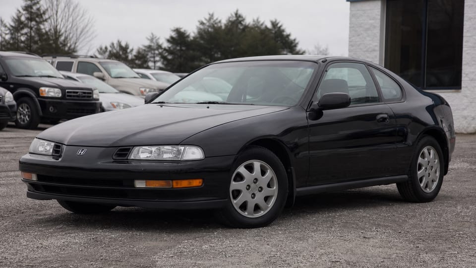 A dark red fourth-generation Honda Prelude coupe parked outdoors.