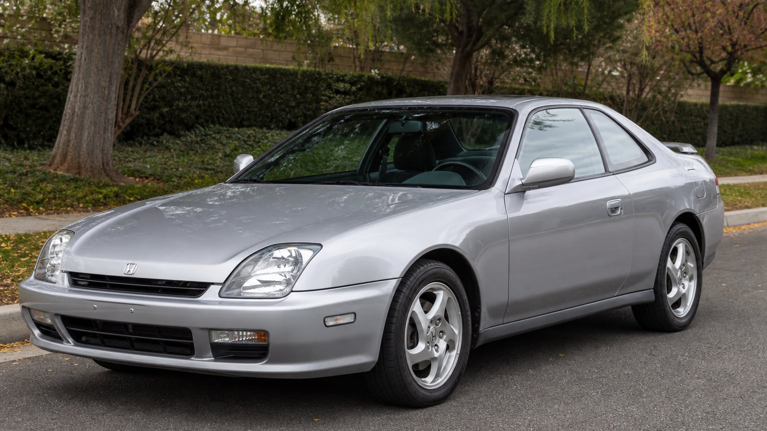 A silver fifth-generation Honda Prelude sport coupe parked on a suburban street.
