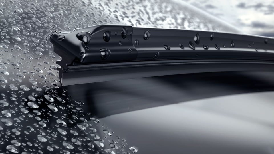 rain drops on the windshield of a car.|a person is holding a car door handle.