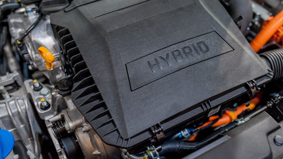 a close up of the engine of a car.|a hand holding a car key with a green leaf on it.|a close up of the engine of a car.