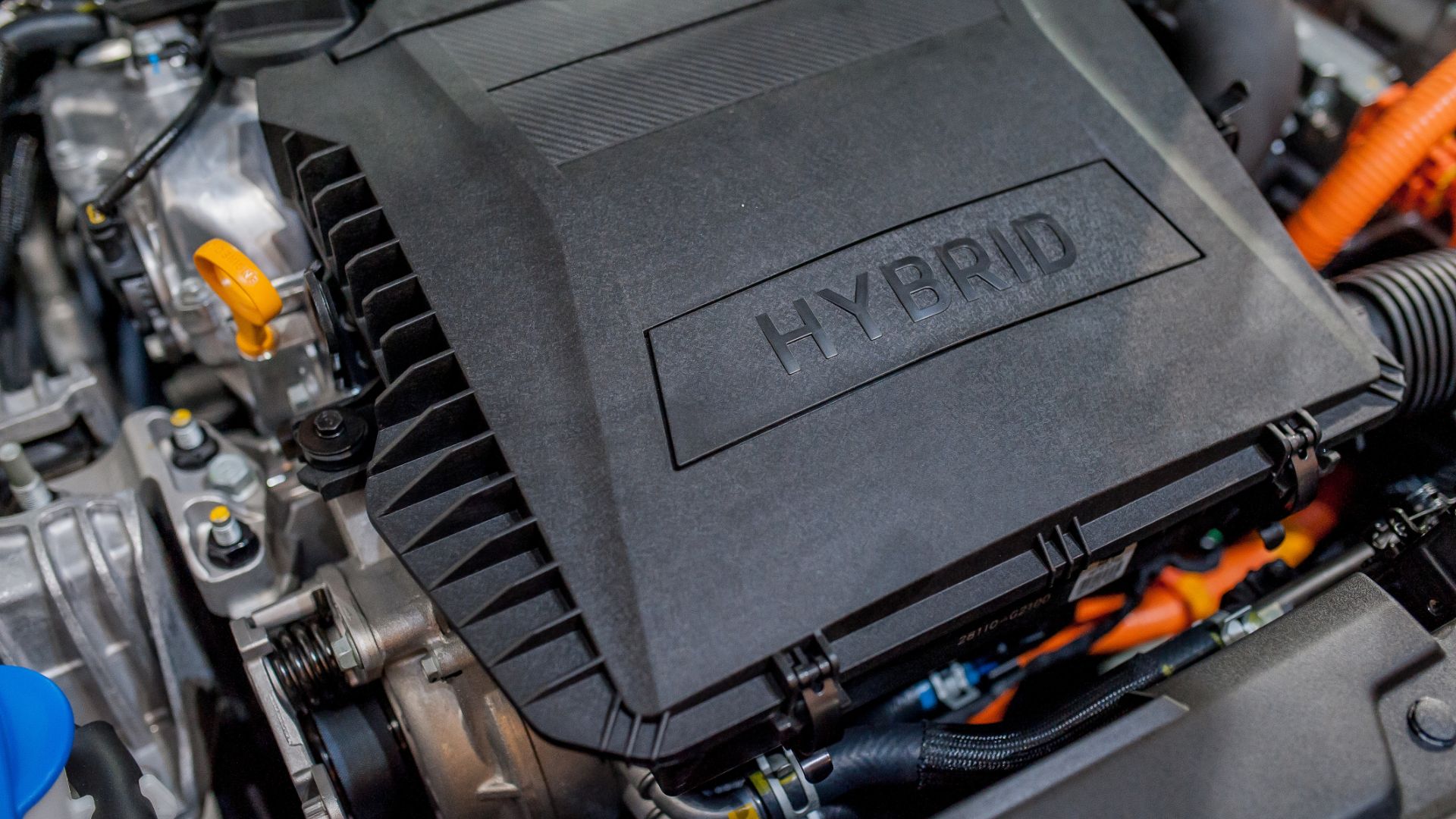 a close up of the engine of a car.|a hand holding a car key with a green leaf on it.|a close up of the engine of a car.