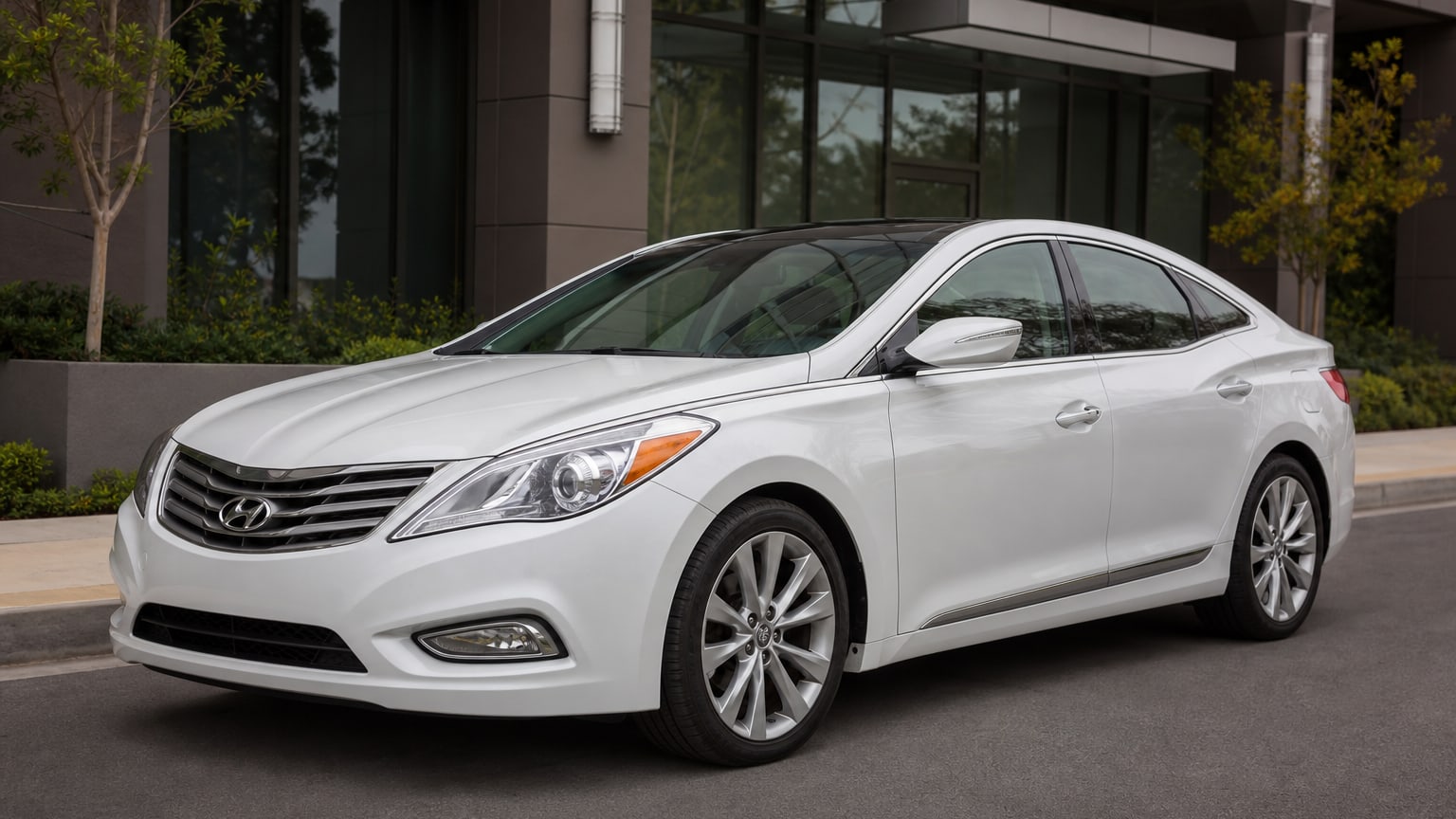 A silver mid-2010s Hyundai Azera sedan parked outside an office building.