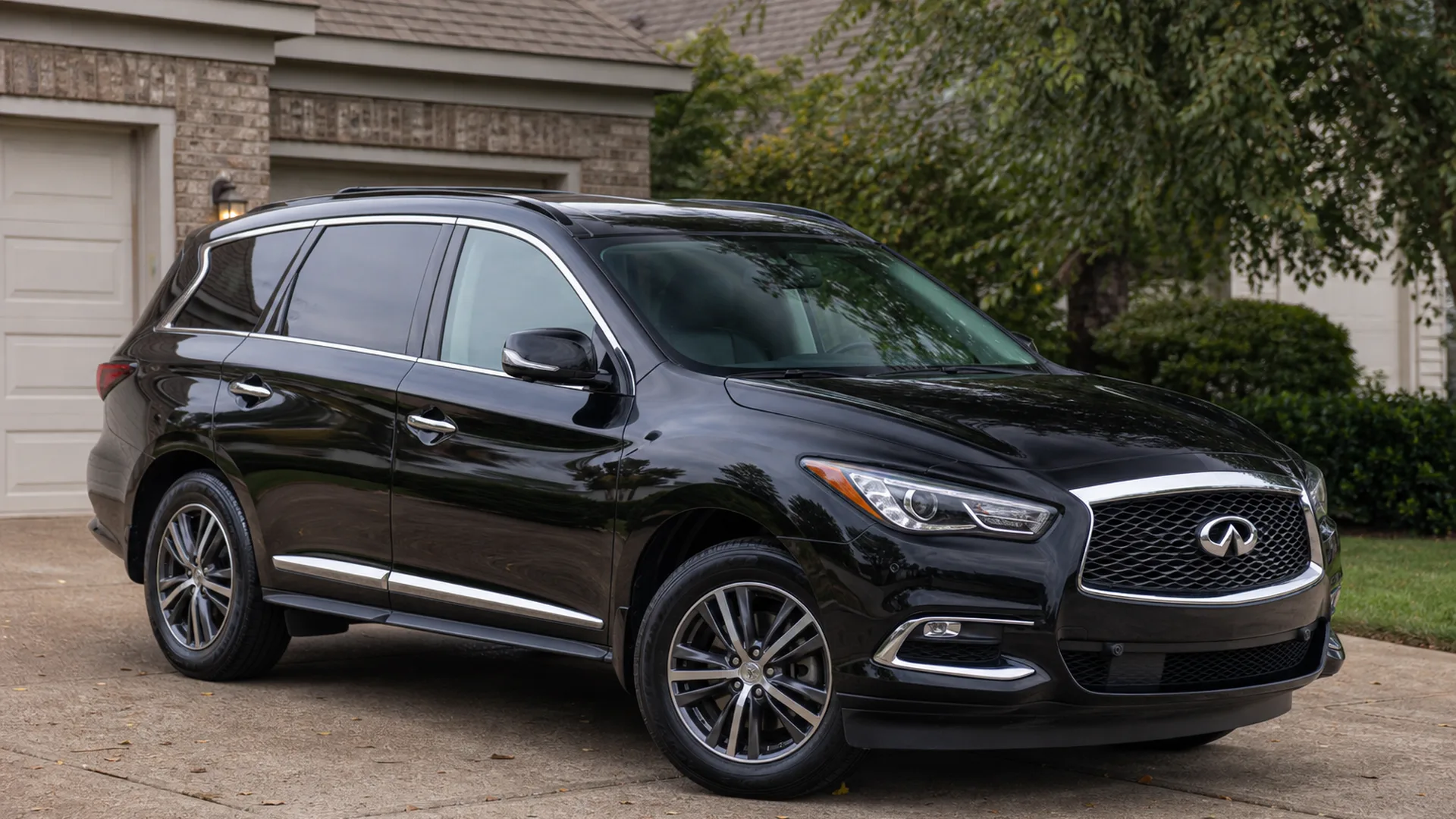 A black Infiniti QX60 SUV parked on a driveway.