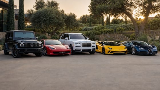 Lineup of a red Ferrari, yellow Lamborghini Aventador, black Mercedes G-Wagon, white Rolls-Royce Cullinan, and blue Bugatti on a private driveway.